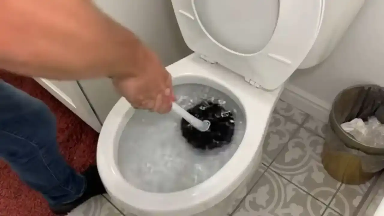 Plunger working in a toilet bowl full of water