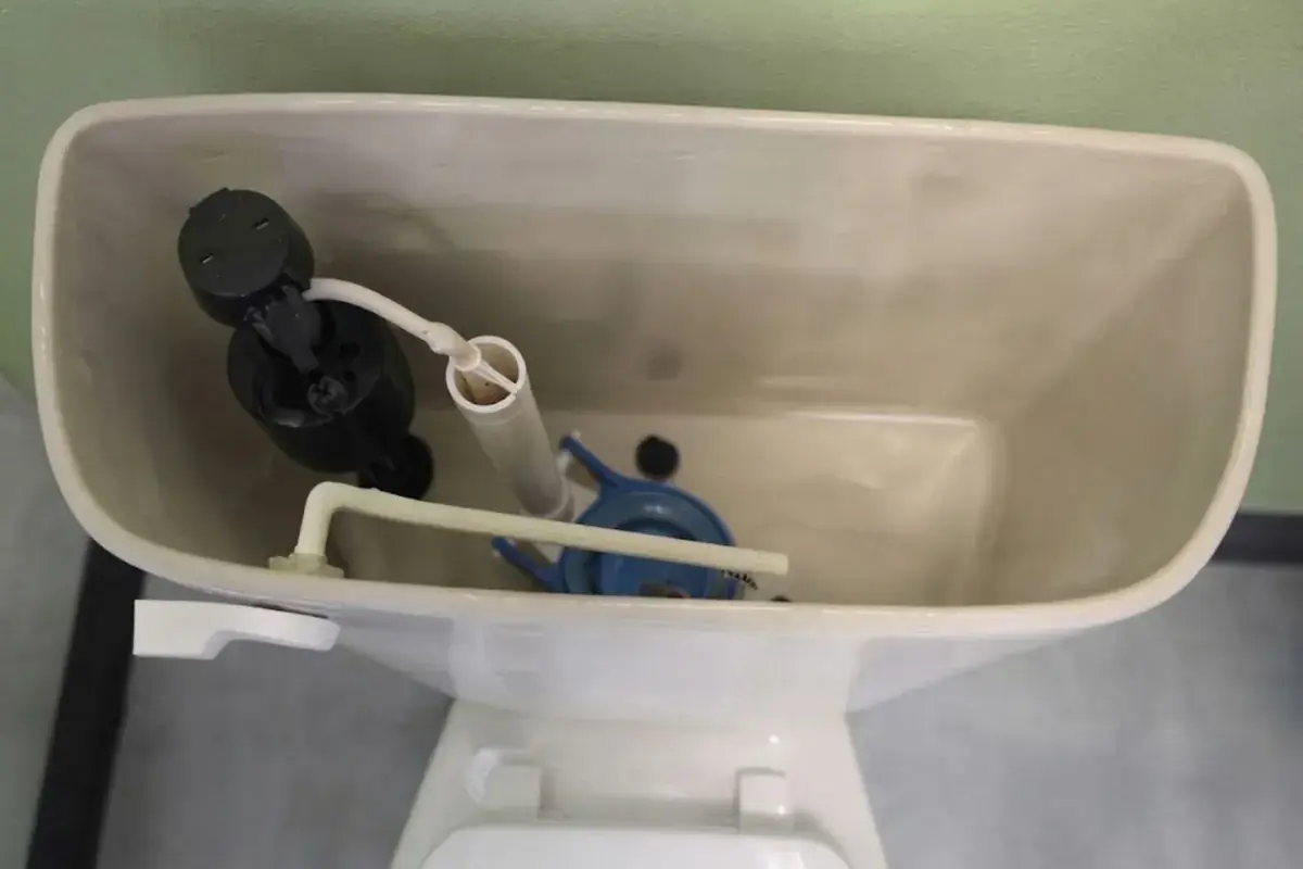 Inside of a toilet tank showing the fill valve, flapper and overflow tube