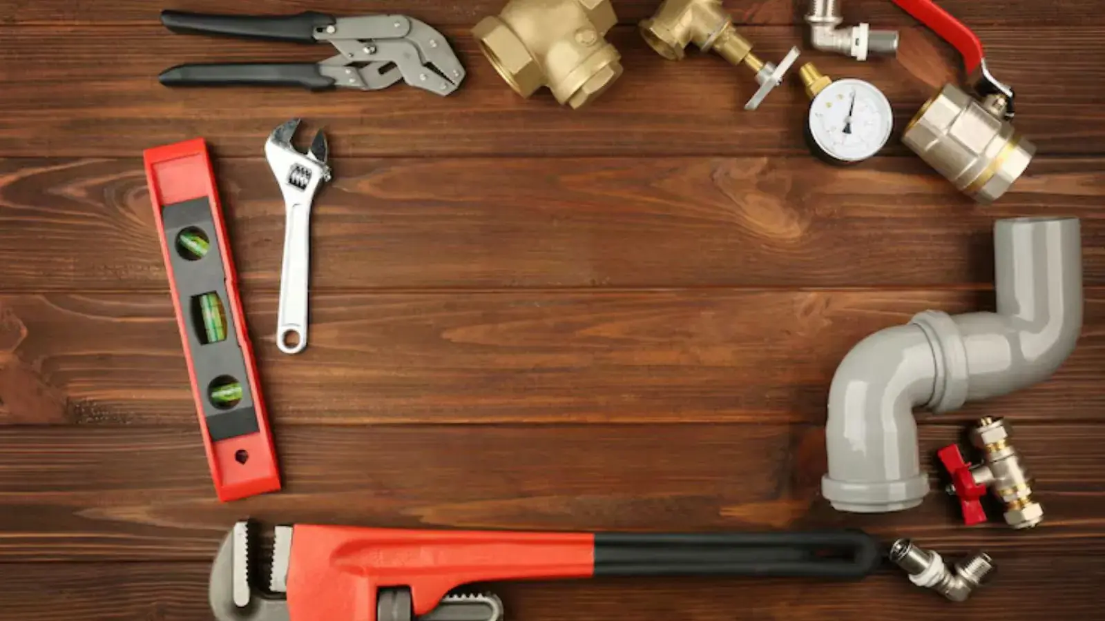 Plumbing tools and brass fittings arranged on a dark wood surface